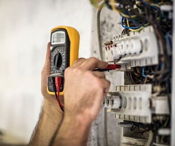 Detail shot of electrician testing voltage on a fuse box on construction site.